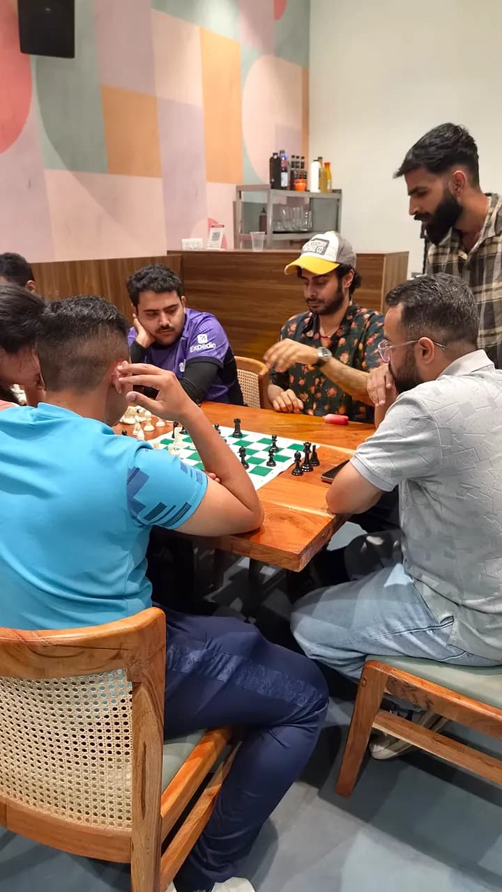 Members leaning in over a chess game at Xircl. while others look on